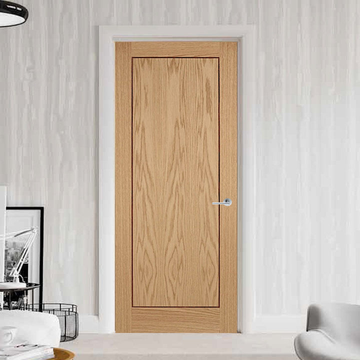 Flush inlay Oak internal door with white frame and architrave, the inlay  on the door creates a vertical border around the door, the walls are white with a grey sofa chair to the bottom right of the image and some home furnishings to the bottom left