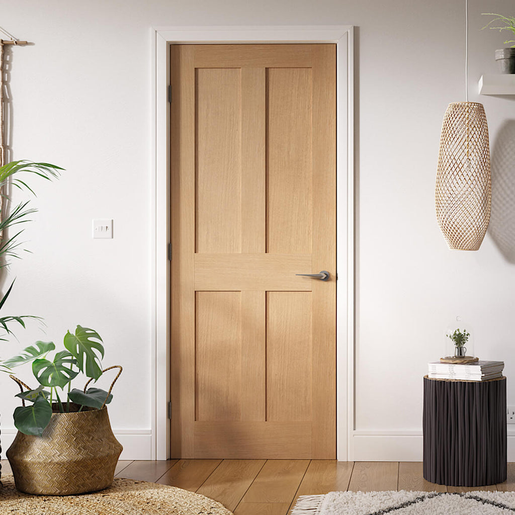 London Oak Internal Door Fully Finished - A contemporary oak style internal door with four flat panel, the door frame and architrave along with the walls are all white, the floor is in oak Oak with rattan pendant light and plants to the left of the image