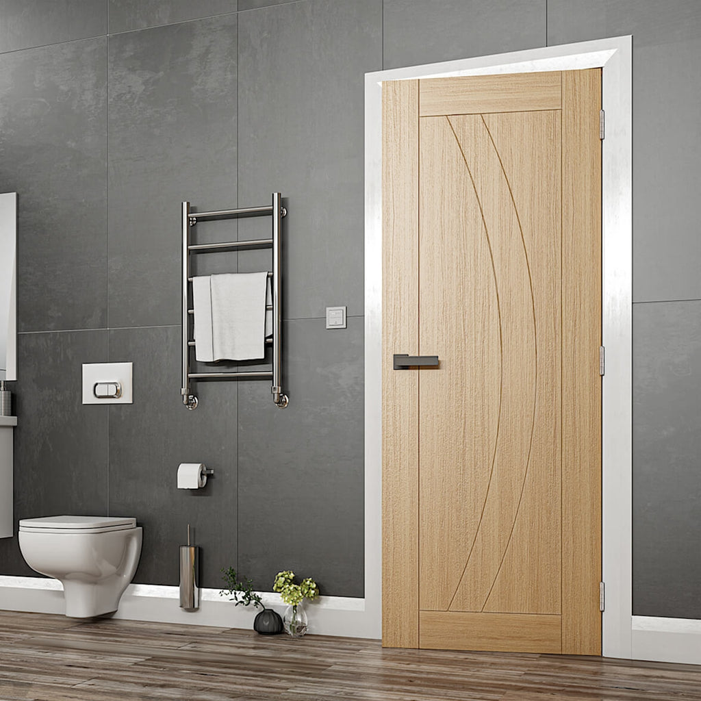 Ravello Oak Internal Door - Oak fire rated door with a grooved arched design, the frame and skirting are all white with dark walls and a textured laminate flooring, there is also a bathroom suit to the left of the door image.
