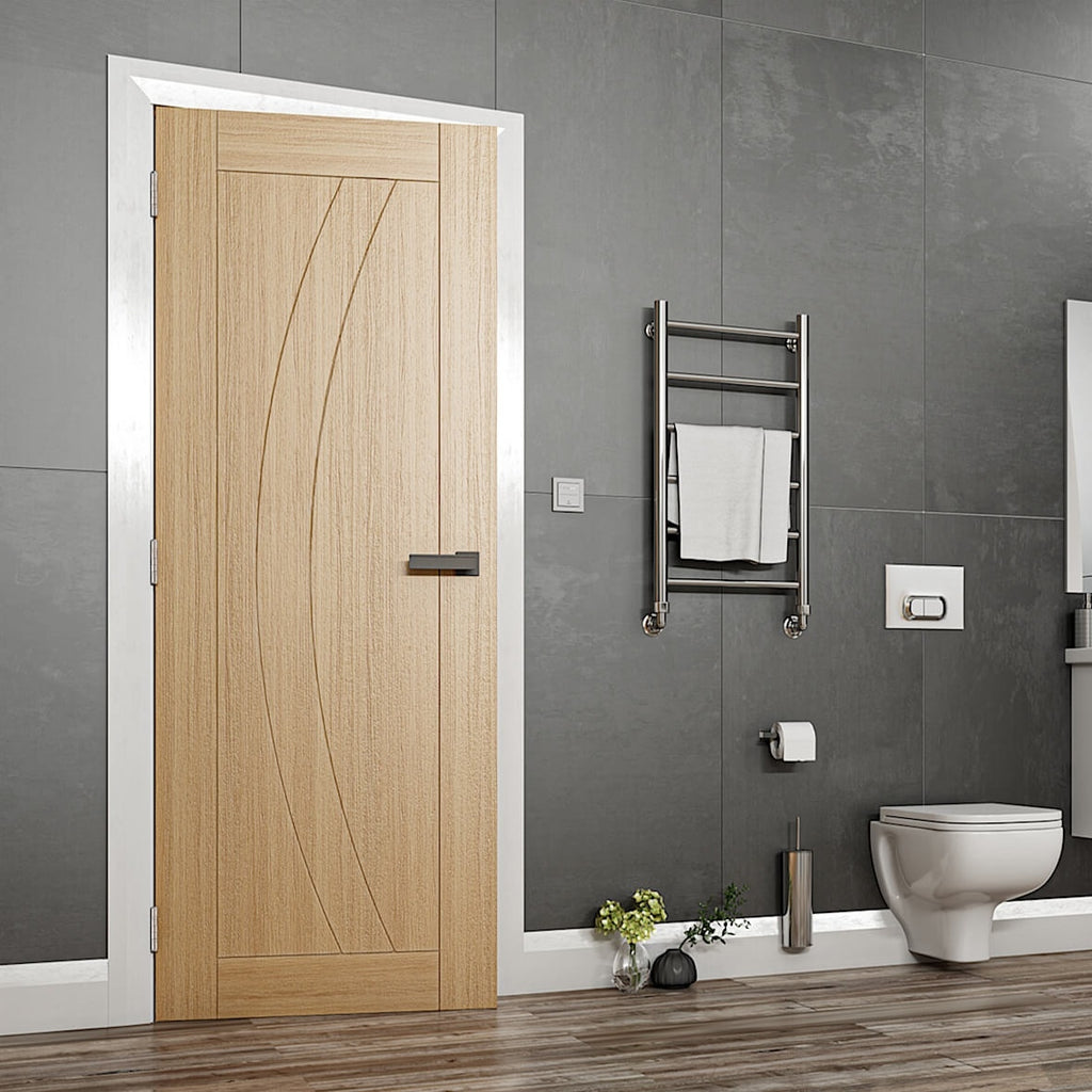 Ravello Oak Fire Door - Oak fire rated door with a grooved arched design, the frame and skirting are all white with dark walls and a textured laminate flooring, there is also a bathroom suit to the right of the door image.