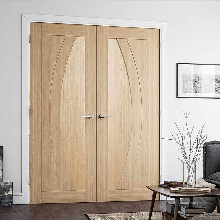 Ravello Oak Door Internal Door Pair - This particular door design features a semi circle to one side on the door, when used as a pair of doors this forms a circle design in the centre, the flooring and table accessories are all in a dark wood colour with off white walls and white architrave and door frames.